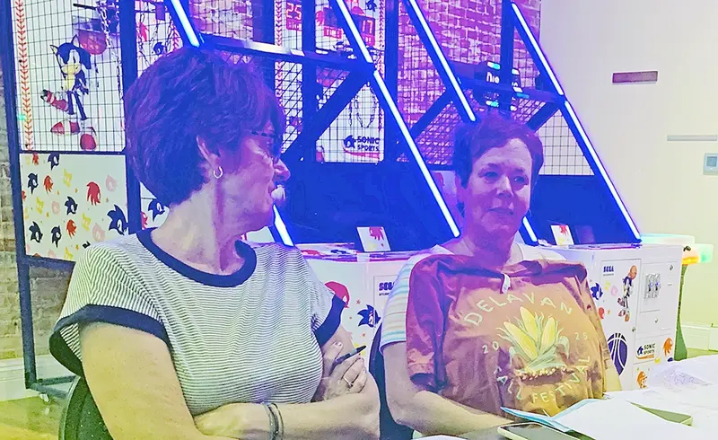 Fall Festival Vice President Beth Zimmer (left) looks on as Lori Leskovisek (right) models the official t-shirt design.