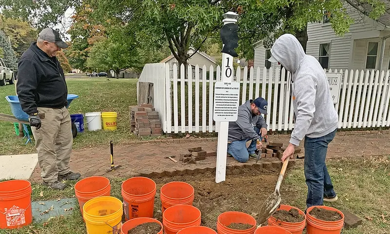 From left, Brian Cunningham, Josh Horning, and Landon Horning remove the edging and begin excavation to extend the herringbone brick sidewalk in front of the Colony House, preparing the site for the newly updated Lincoln Mile Post #10.
