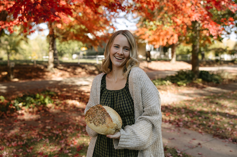 Reka Brooks, owner of Little Piggy Bakery, showcases her freshly baked Harvest Seeded Sourdough loaf—an autumn favorite crafted with care and perfect for the Thanksgiving table.