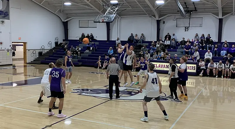 Jason Fisher of the “Old” team rises for the opening tip against Prescott Jeckel of the “Young” squad, sending the ball cleanly to teammate Dan Mammen as the annual Delavan Alumni Game gets underway.