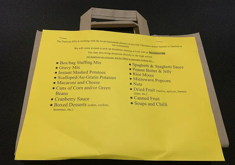 A Doorstep Donation Kit awaits pickup, filled with non-perishable goods like stuffing mix, canned vegetables, and boxed desserts. Every item helps build a holiday meal for a local family in need.