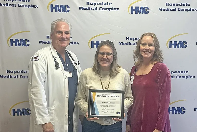 Dr. Matthew Rossi, CEO of Hopedale Medical Center (left), and Emily Whitson, COO (right), present Natalie Lessen (center) with her November Employee of the Month Certificate in recognition of her nine years of dedicated service at Miss Mona’s Child Care Center.
