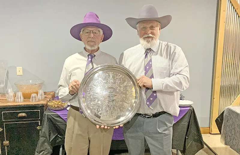 Coach John Wiser (left), proudly wearing his trademark purple cowboy hat, shares a moment with his 1976–77 state champion, Guy Allen (right).