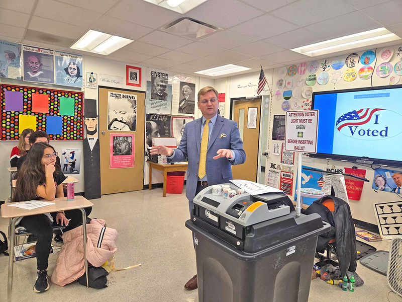 Tazewell County Clerk John Ackerman demonstrates the security features of local election equipment to students at Pekin Community High School during a “Help America Vote Day” visit focused on civic engagement and poll?worker recruitment.
