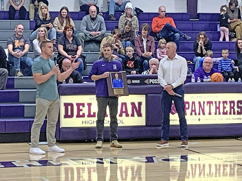 Jason Fisher (left) and Brady Wildenradt (center) present the Wall of Fame plaque to their former coach, Ryon Kramer (right), honoring his lasting impact on Delavan basketball.