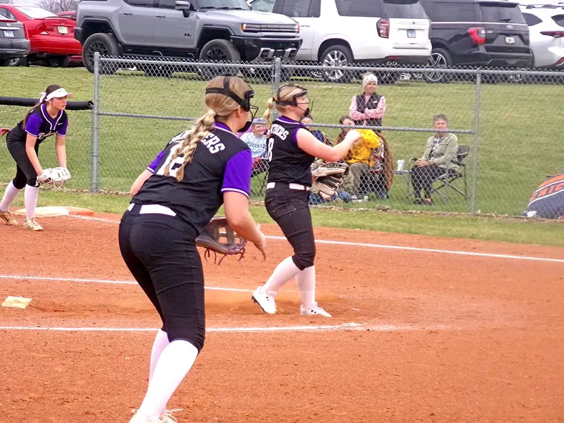 Mia Mammen fires a pitch from the mound as Addi Fisher at first and Maddie Lowers at third stay poised for the play.
