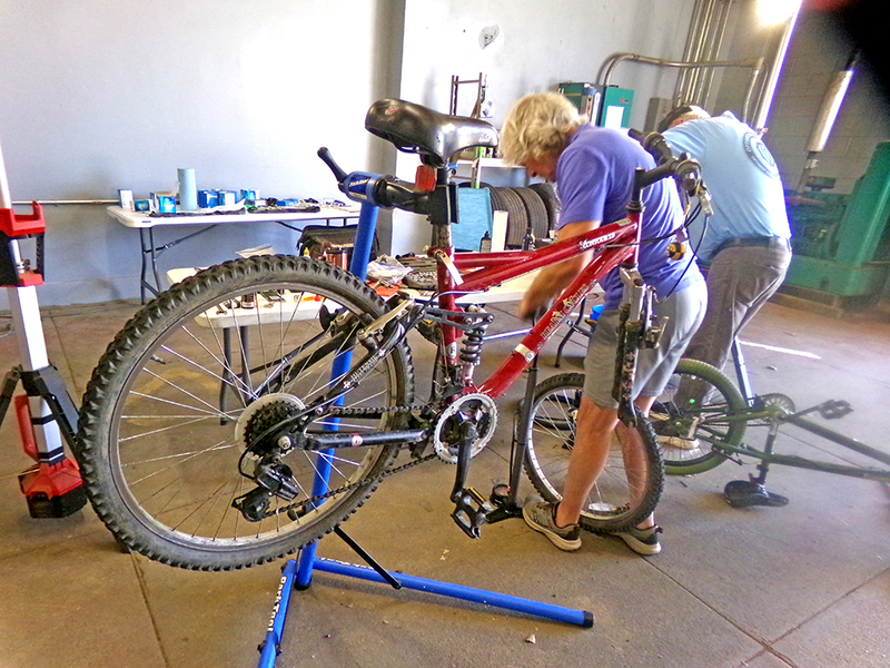 John Eigenbrod (left) and Pete Ross (right) stay busy at the annual Bike Repair Clinic, each tackling a different bicycle as they help local kids get road-ready for spring