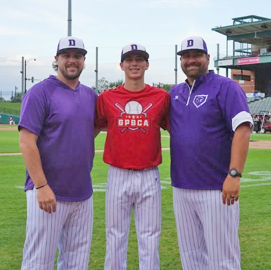Coach Sam Hodges (left) and Coach Dillon Hodges (right) join Delavan standout Corbin Soldal (center) on the field at Dozer Park during the 2026 GPBCA All-Star Game in Peoria on June 23.